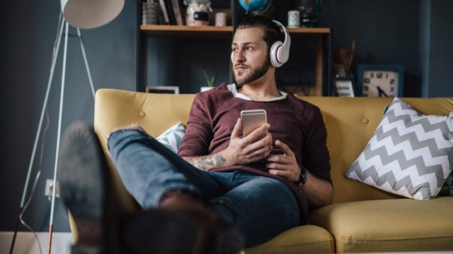 Junger Mann sitzt auf Couch und hört den Podcast UI Insights.